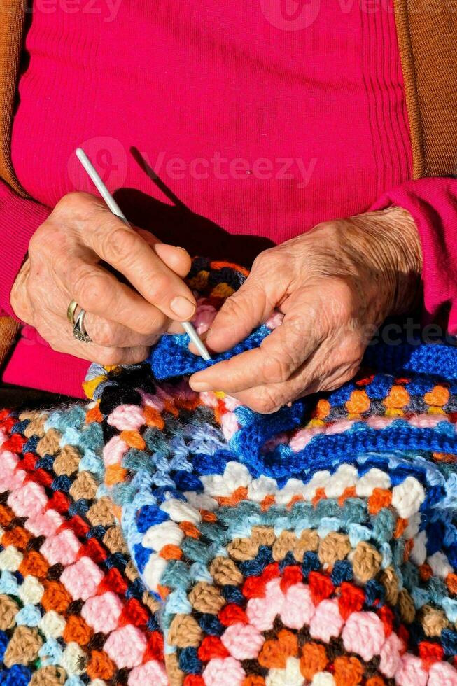 een ouder vrouw is haken een kleurrijk deken foto