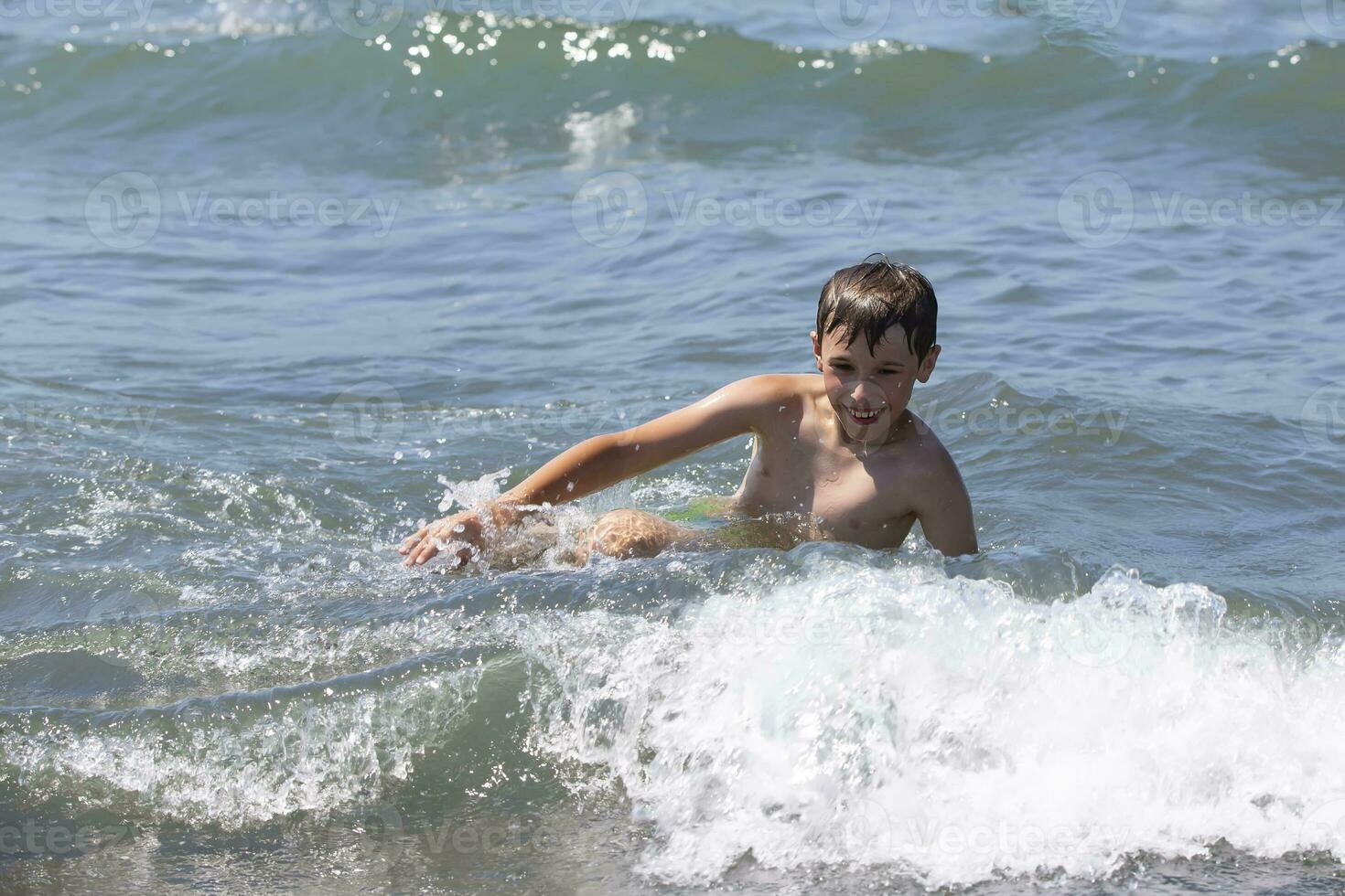 gelukkig jongen zwemt in de zee, Toneelstukken met de golven. kind Aan vakantie Bij de kust. foto