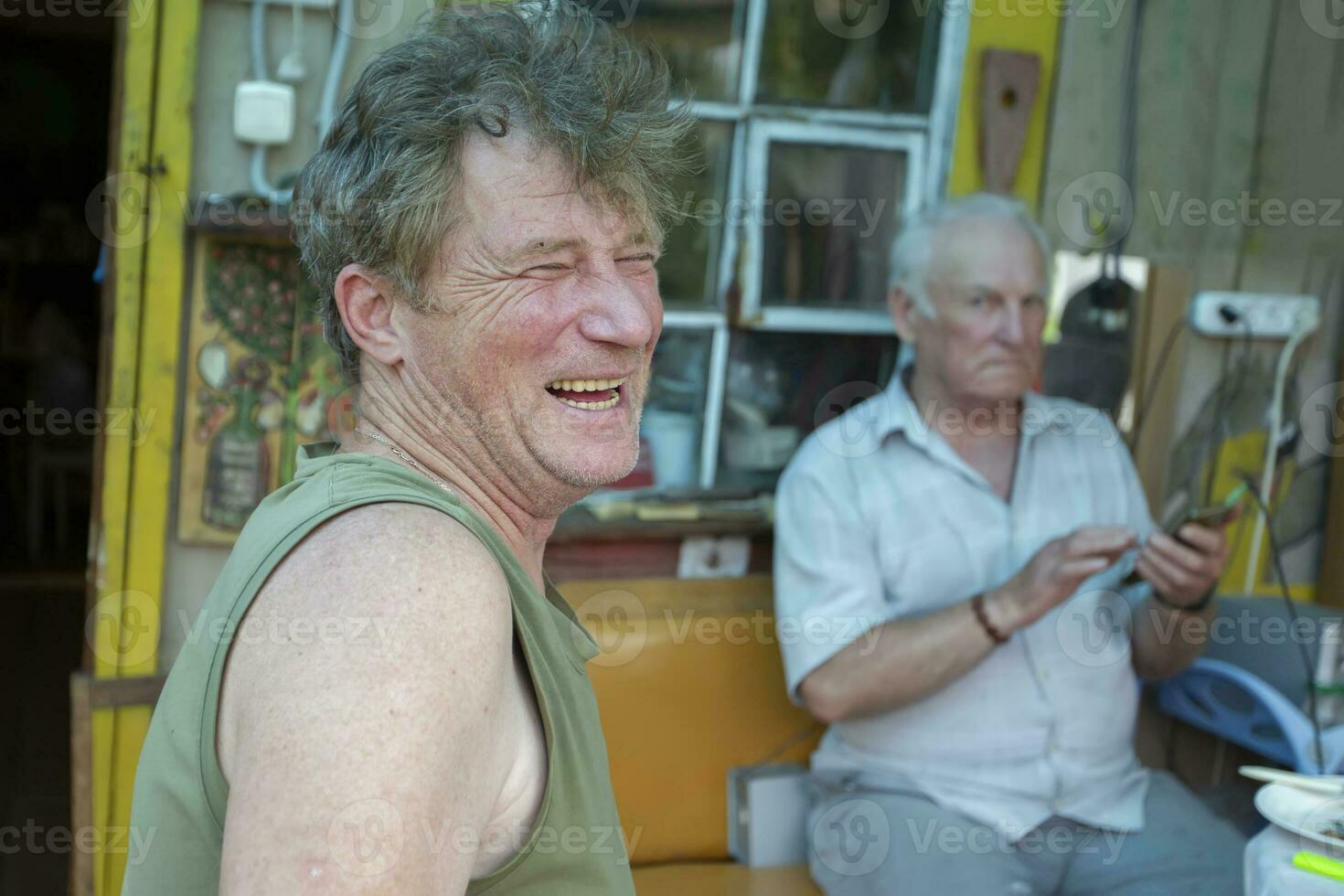 een volwassen zoon lacht vrolijk tegen de achtergrond van een ouderen oud man's vader. vader en zoon. foto