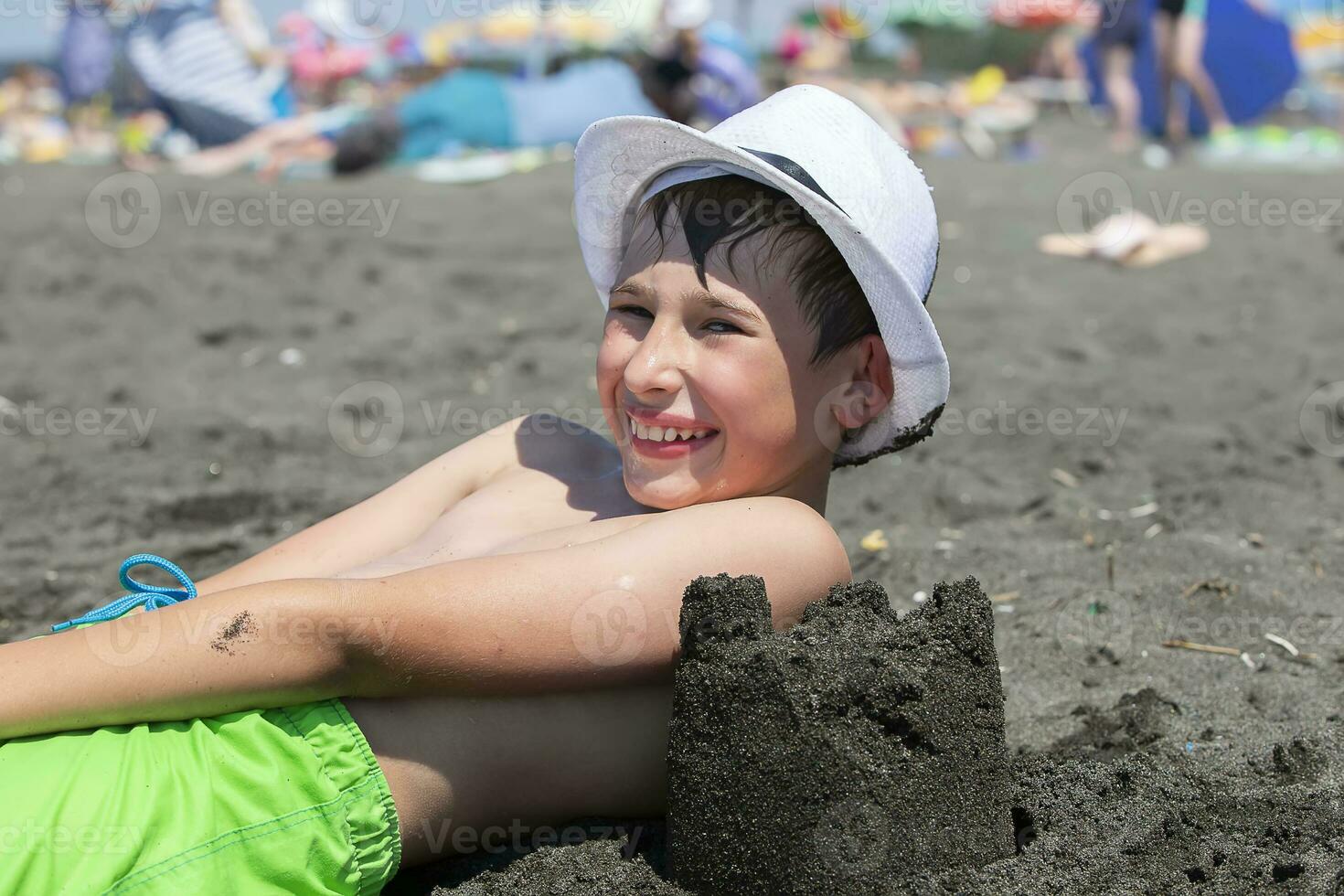 gelukkig jongen leugens Aan de strand met zwart magnetisch zand. foto