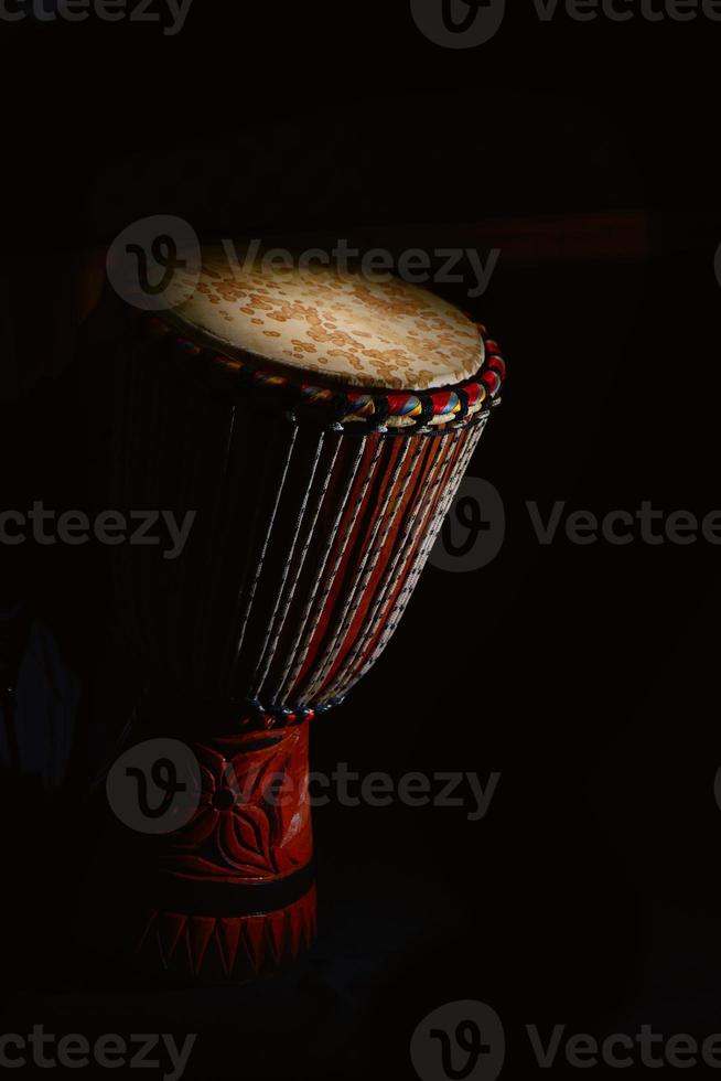 djembe percussie gedeeltelijk verlicht op een zwarte achtergrond foto