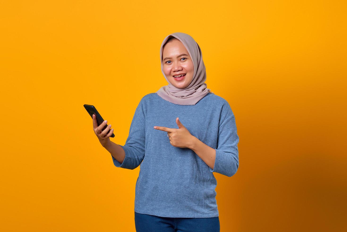 opgewonden aantrekkelijke aziatische vrouw wijzende vinger naar mobiele telefoon foto