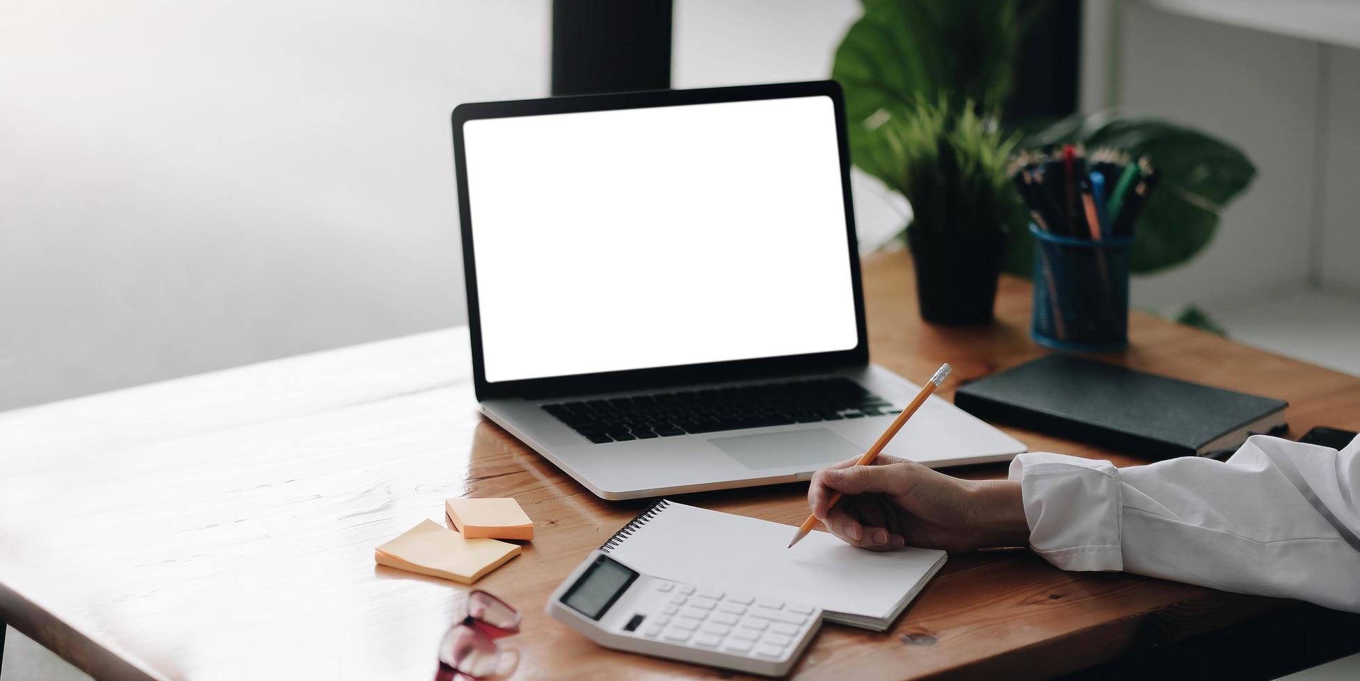 zakenvrouw met behulp van laptop leeg scherm tijdens het werken met rekenmachine foto