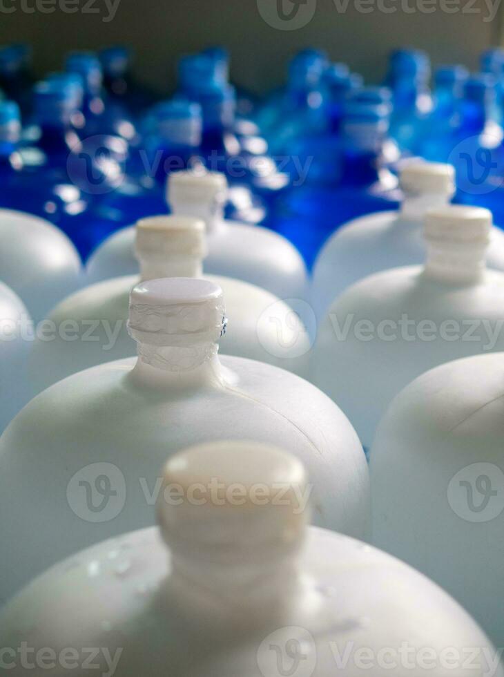 plastic groot flessen of wit en blauw gallons van gezuiverd drinken water binnen de productie lijn. water drinken fabriek foto