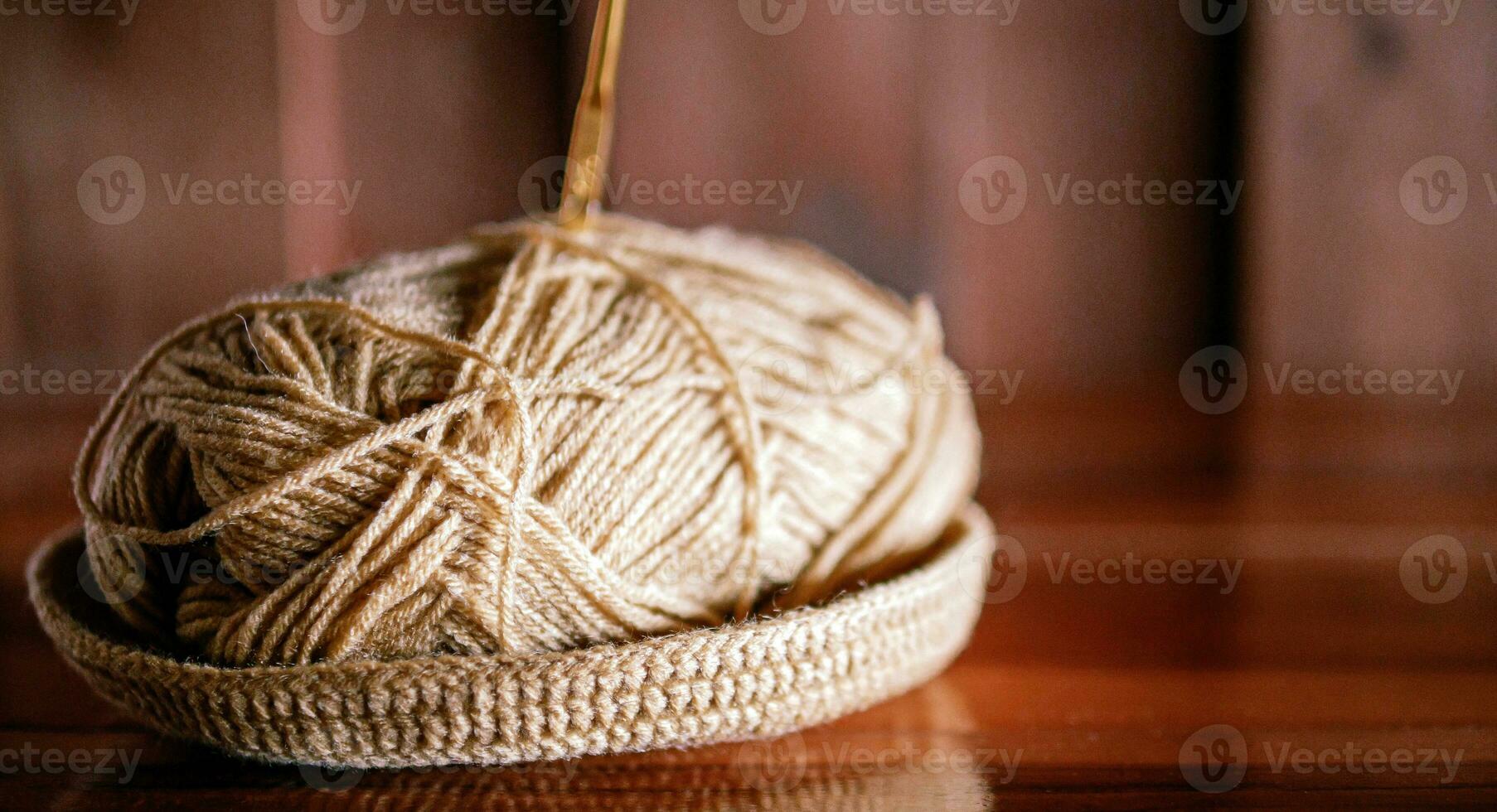 een garen met een breiwerk naald- zit vast in het leugens Aan een houten tafel, hobby ambachten met garen, hand- gemaakt. foto