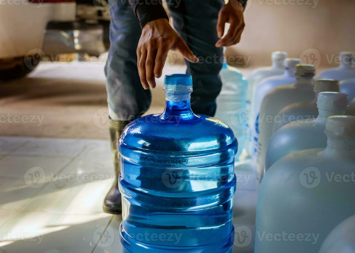 arbeiders optillen drinken water Doorzichtig en schoon in blauw plastic gallon in de terug van een vervoer vrachtauto gezuiverd drinken water binnen de productie lijn naar bereiden voor verkoop.klein bedrijf foto