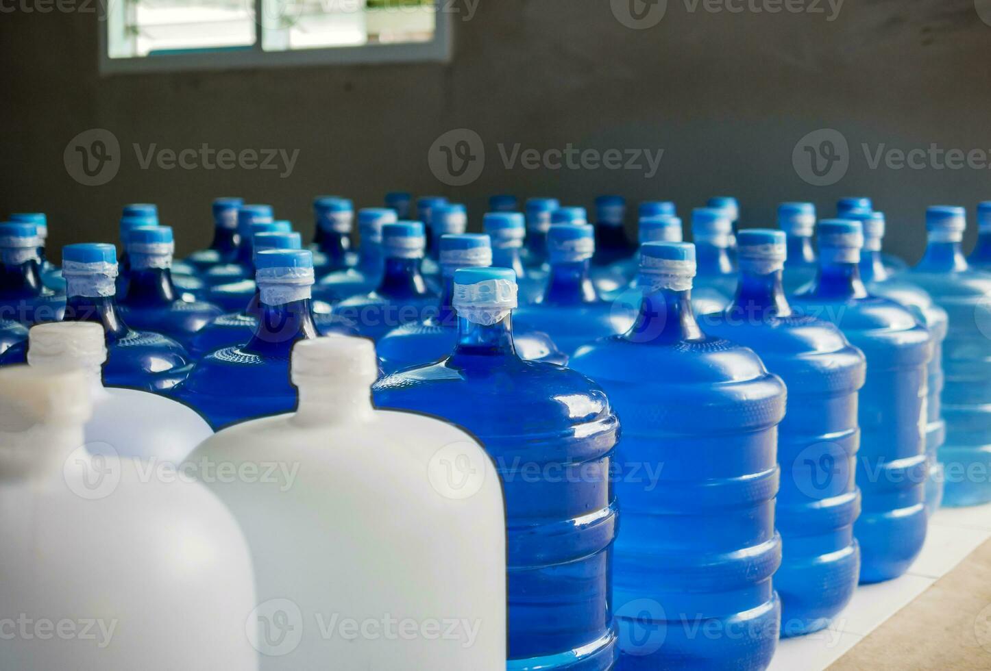 plastic groot flessen of wit en blauw gallons van gezuiverd drinken water binnen de productie lijn. water drinken fabriek foto