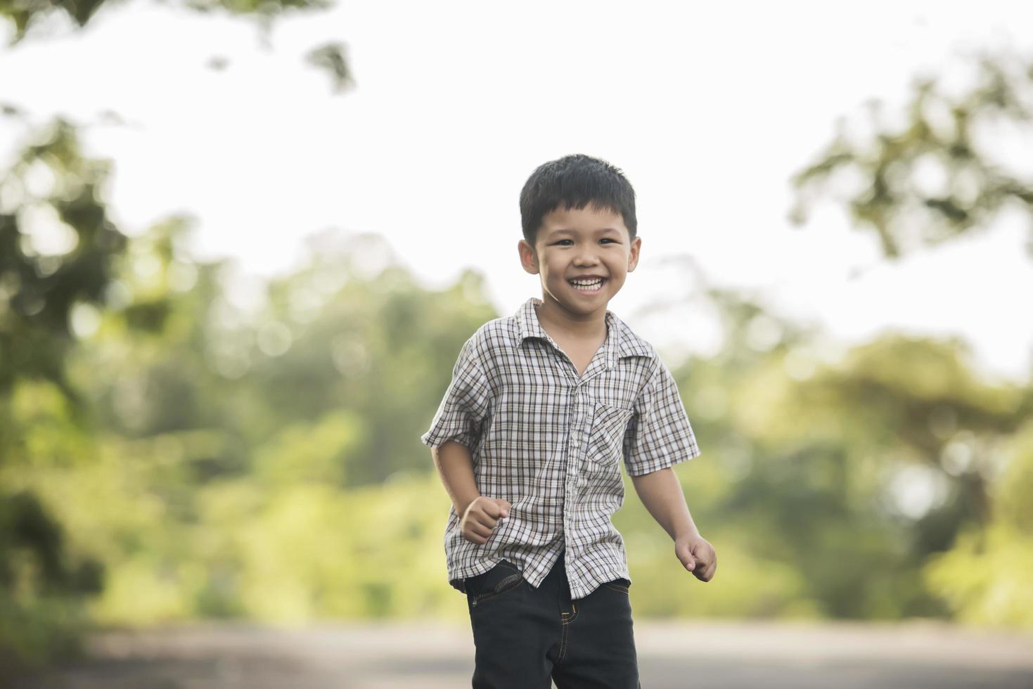 portret van een kleine jongen die in het natuurpark staat en lacht naar de camera. foto