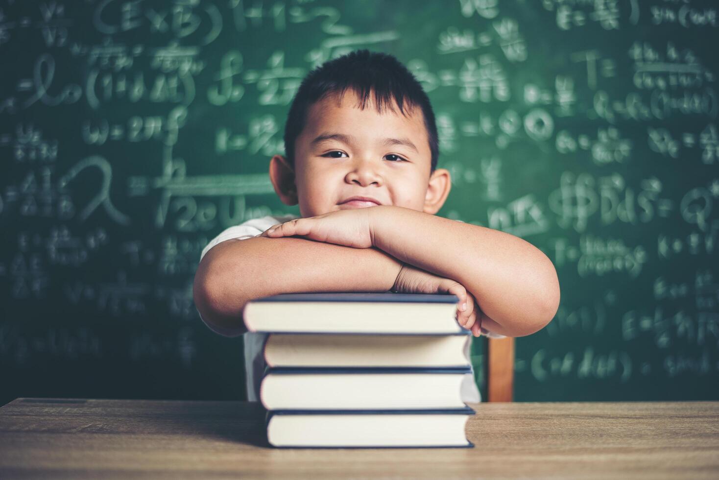 jongen met boeken die in de klas zitten foto