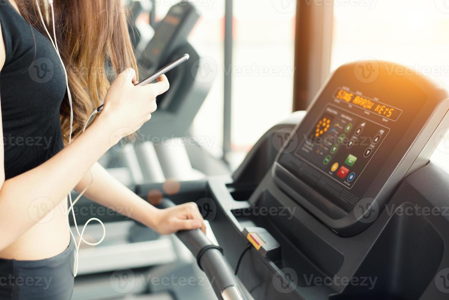 aziatische vrouw die slimme telefoon gebruikt tijdens het sporten foto