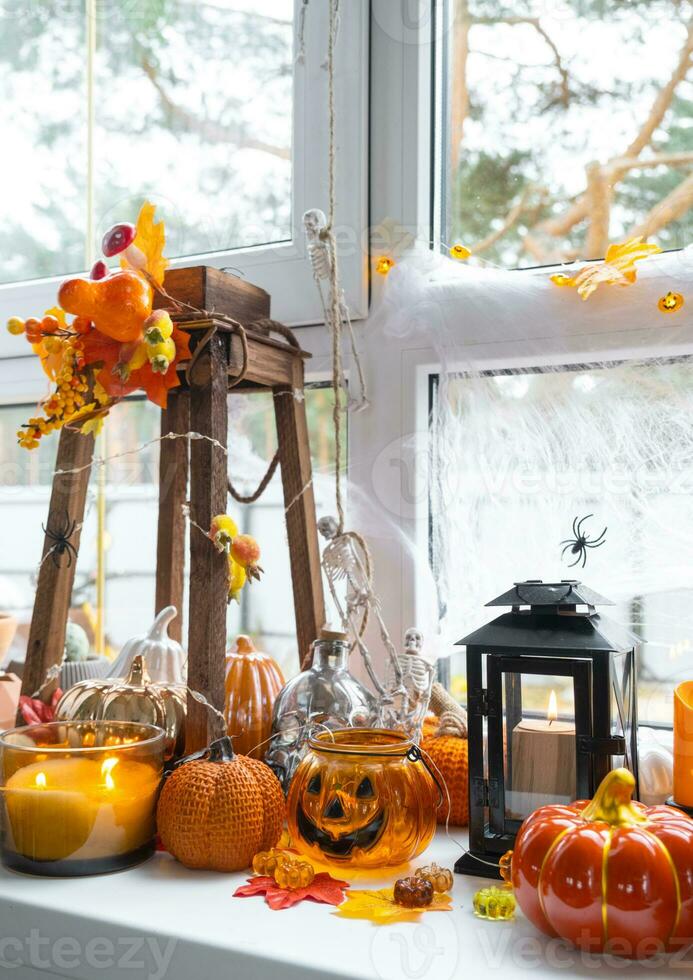 feestelijk decor van de huis Aan de vensterbank voor halloween - pompoenen, jack O lantaarns, schedels, spinnenwebben, spinnen, skeletten, kaarsen en een slinger - een knus en vreselijk humeur foto