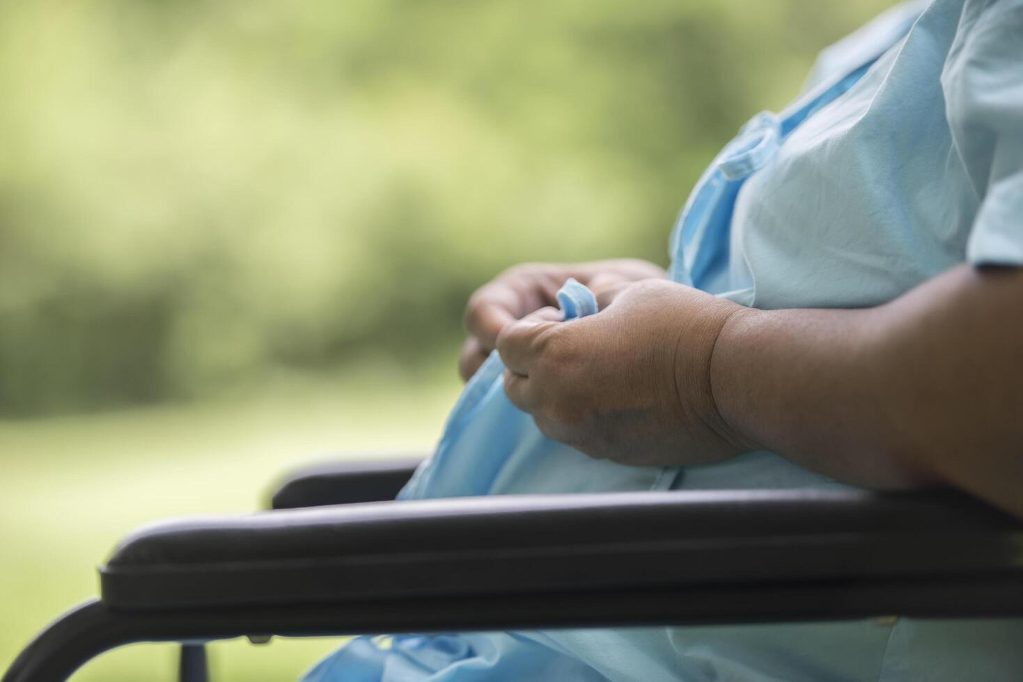 close-up eenzame oudere vrouw zittend op een rolstoel in de tuin foto