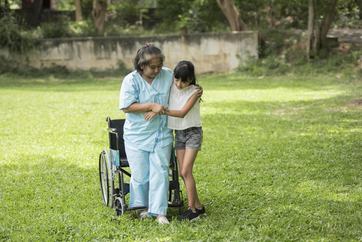 bejaarde grootmoeder in rolstoel met kleindochter in het ziekenhuis foto