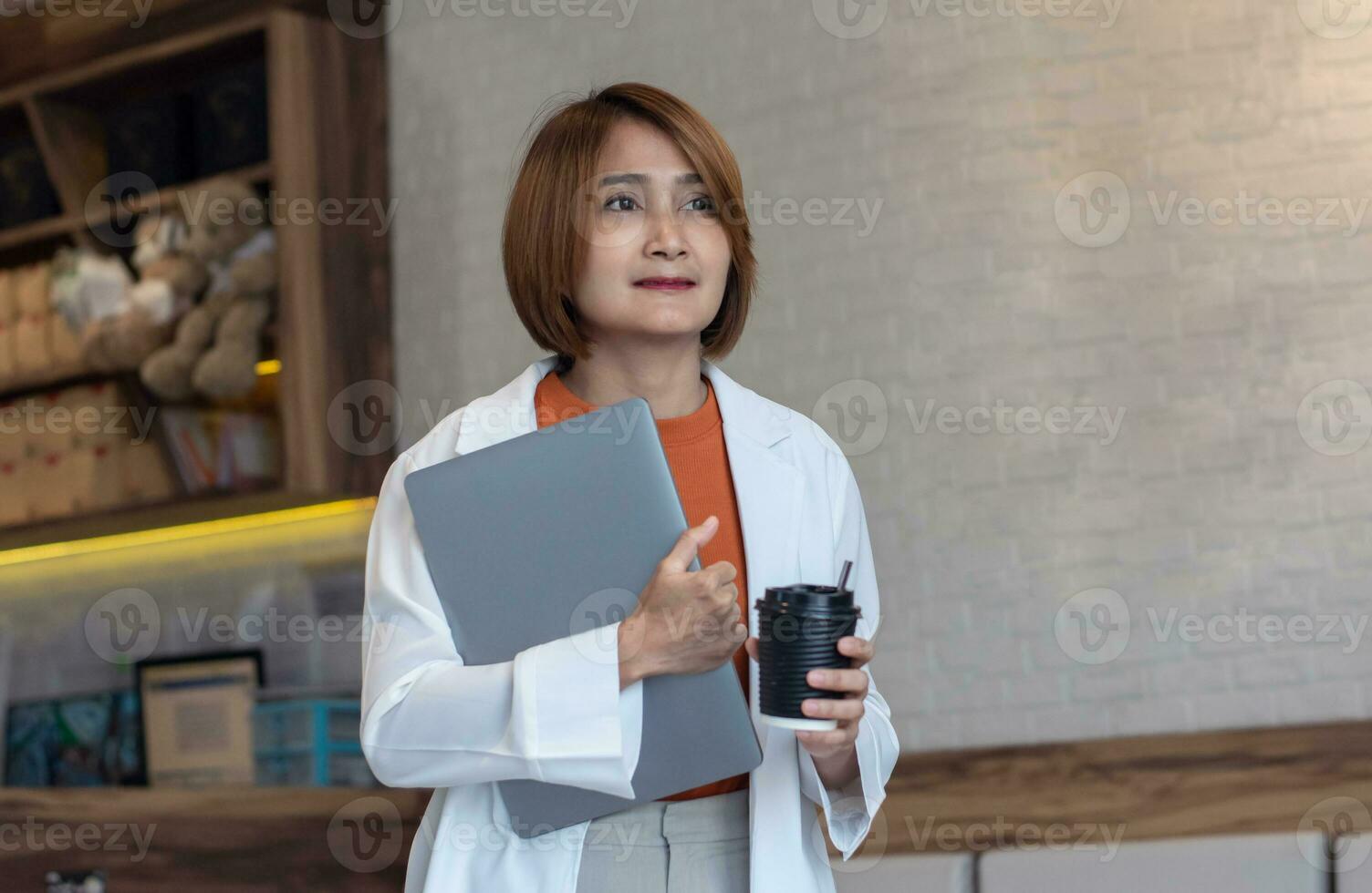 zakenvrouw vervelend wit pak jasje Holding laptop en buying koffie meenemen heet drinken wandelen uit de cafe voor Gaan vergadering klant, levensstijl werk concept. foto