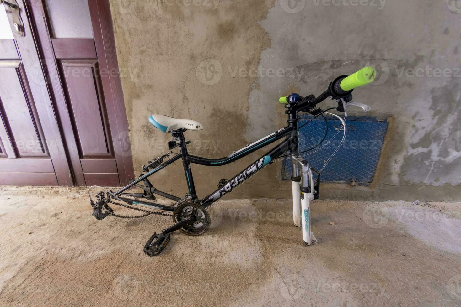 afbeelding van een defecte fiets zonder banden staand in voorkant van een muur foto