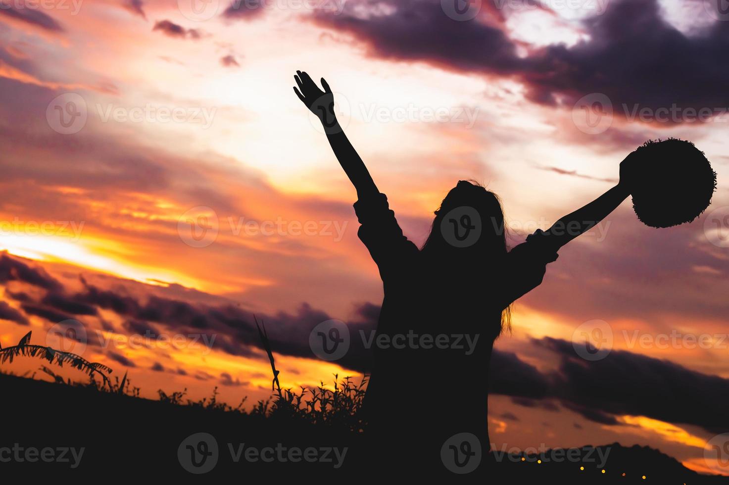 silhouet van gelukkige vrouw met open armen onder zonsopgang aan zee foto