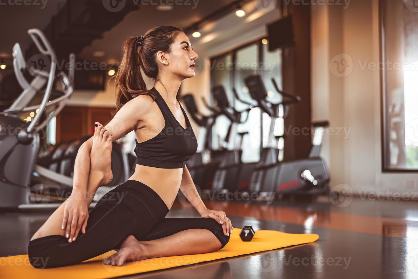 vrouw doet buigende benen yoga in fitness workouts training gym foto
