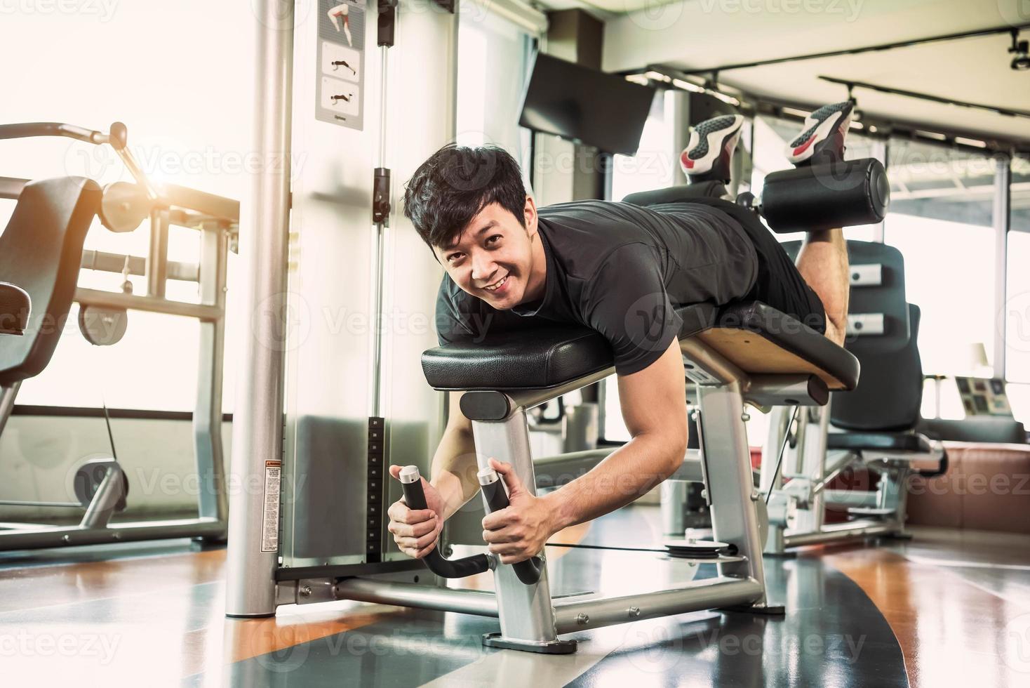 Aziatische sportman die zich uitstrekt en gewicht opheft met twee benen foto