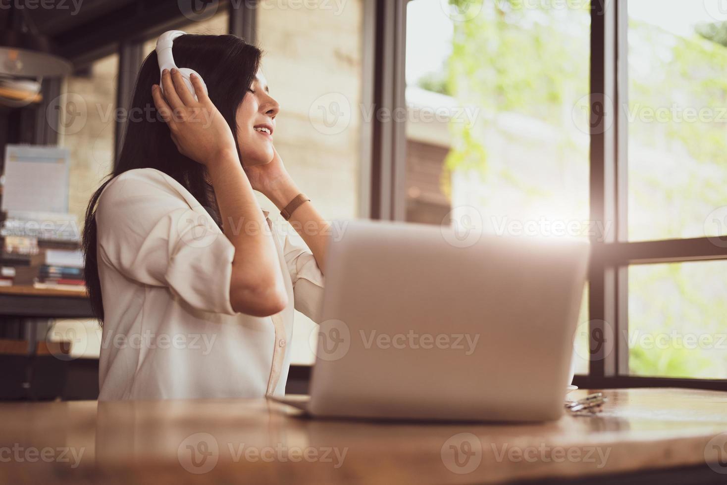 gelukkige aziatische vrouw die ontspant en muziek luistert in de coffeeshop foto