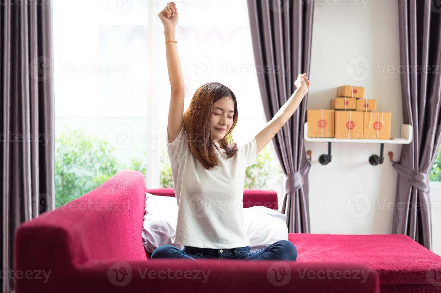 gelukkige jonge Aziatische zakenvrouw zittend op een rode bank en stretching foto
