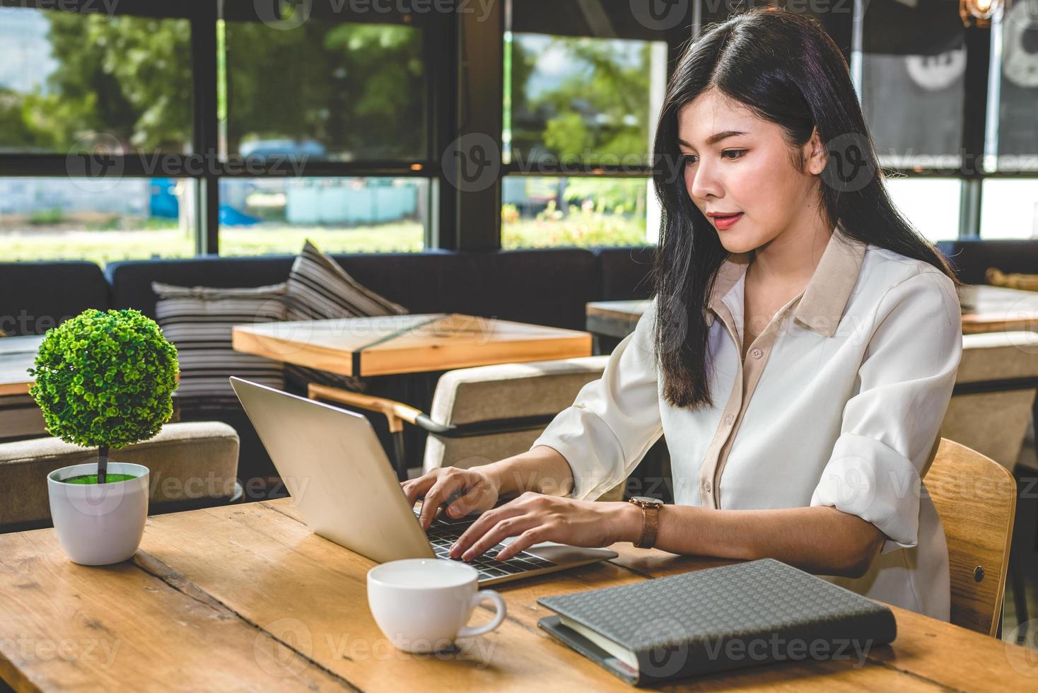 Aziatische vrouw die met laptop in coffeeshop werkt foto