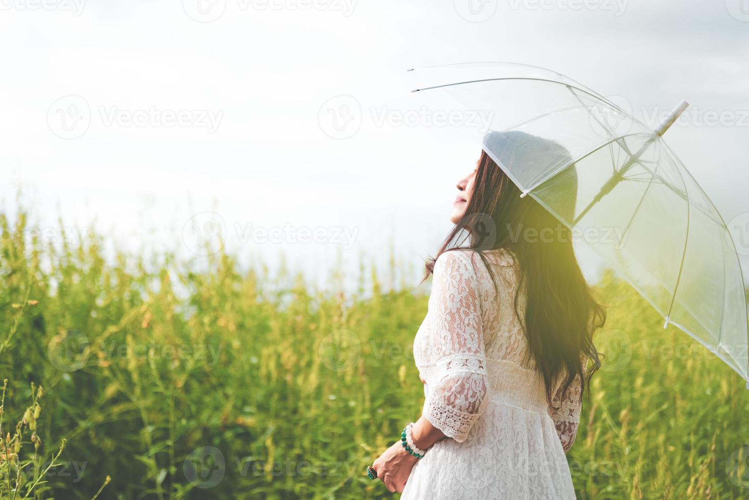 Aziatische vrouw in witte jurk met paraplu in koolzaadveld foto