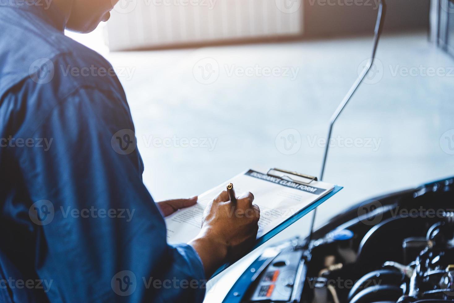 automonteur die klembord vasthoudt en naar onderhoudsvoertuig controleert foto