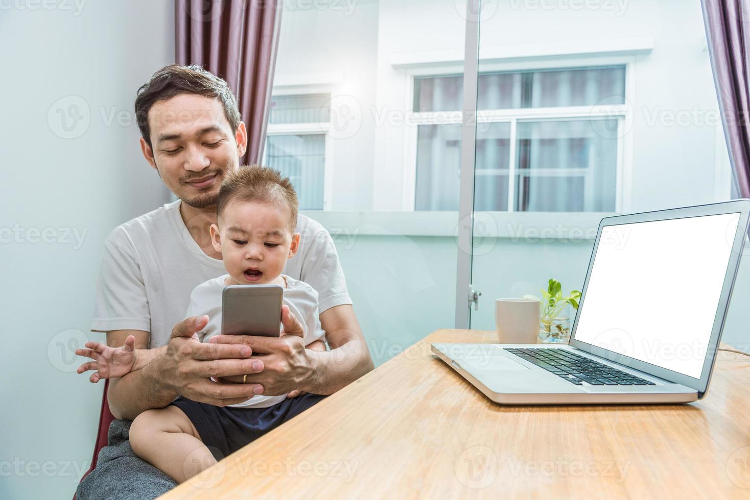 Aziatische vader en zoon die slimme telefoon samen in huis gebruiken foto