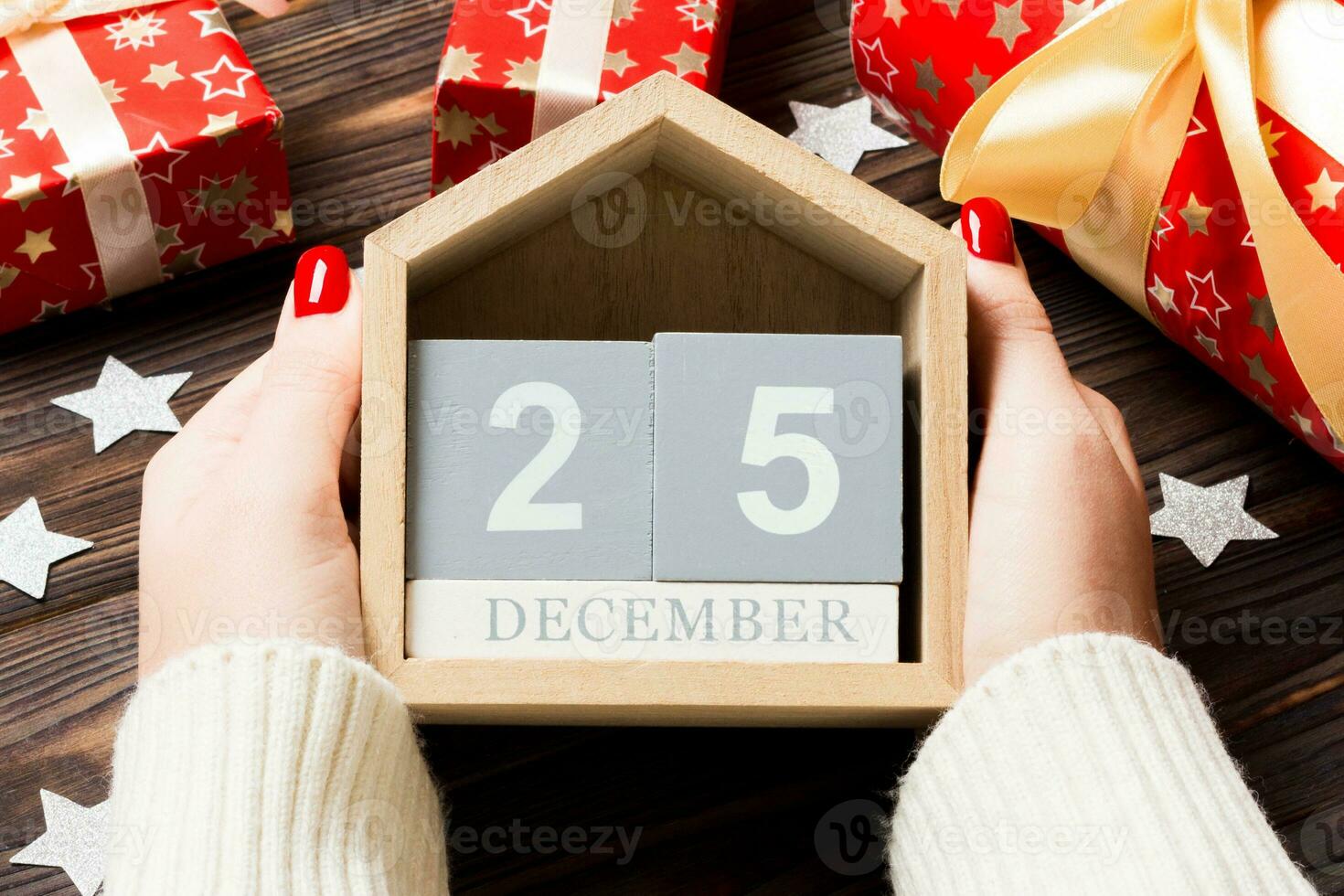 top visie van vrouw handen Holding een kalender Aan houten achtergrond. de twintig vijfde van december. vakantie decoraties. Kerstmis concept foto