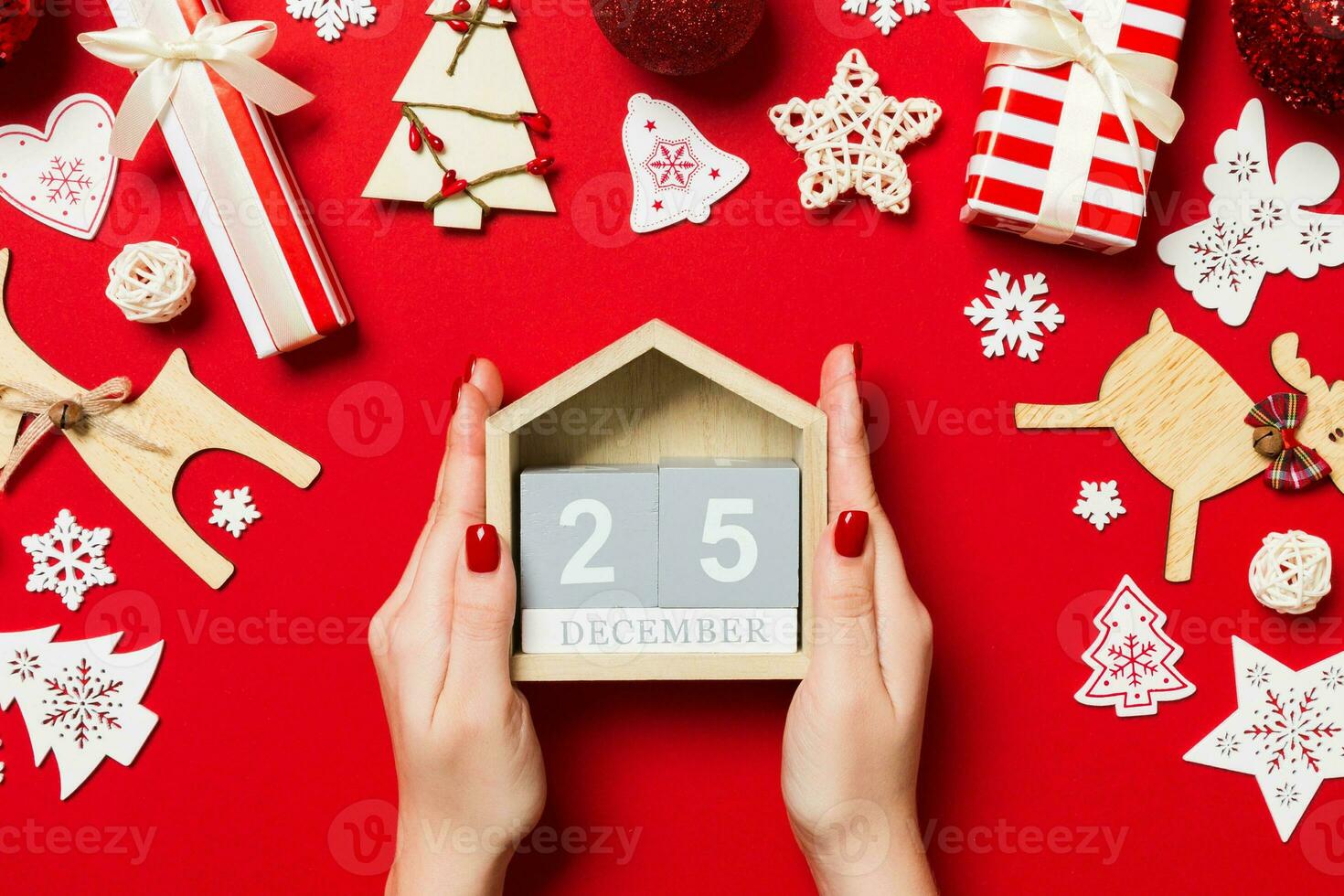 top visie van vrouw handen Holding kalender Aan rood achtergrond. de twintig vijfde van december. vakantie decoraties. Kerstmis tijd concept foto