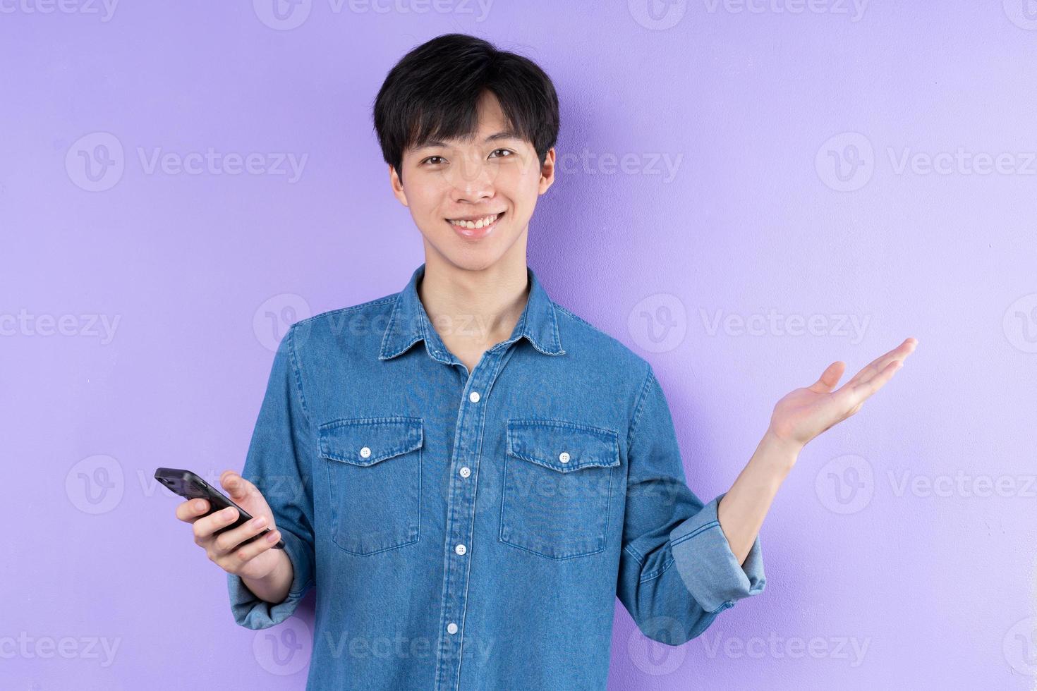 portret van aziatische man in blauw shirt die zich voordeed op paarse achtergrond foto