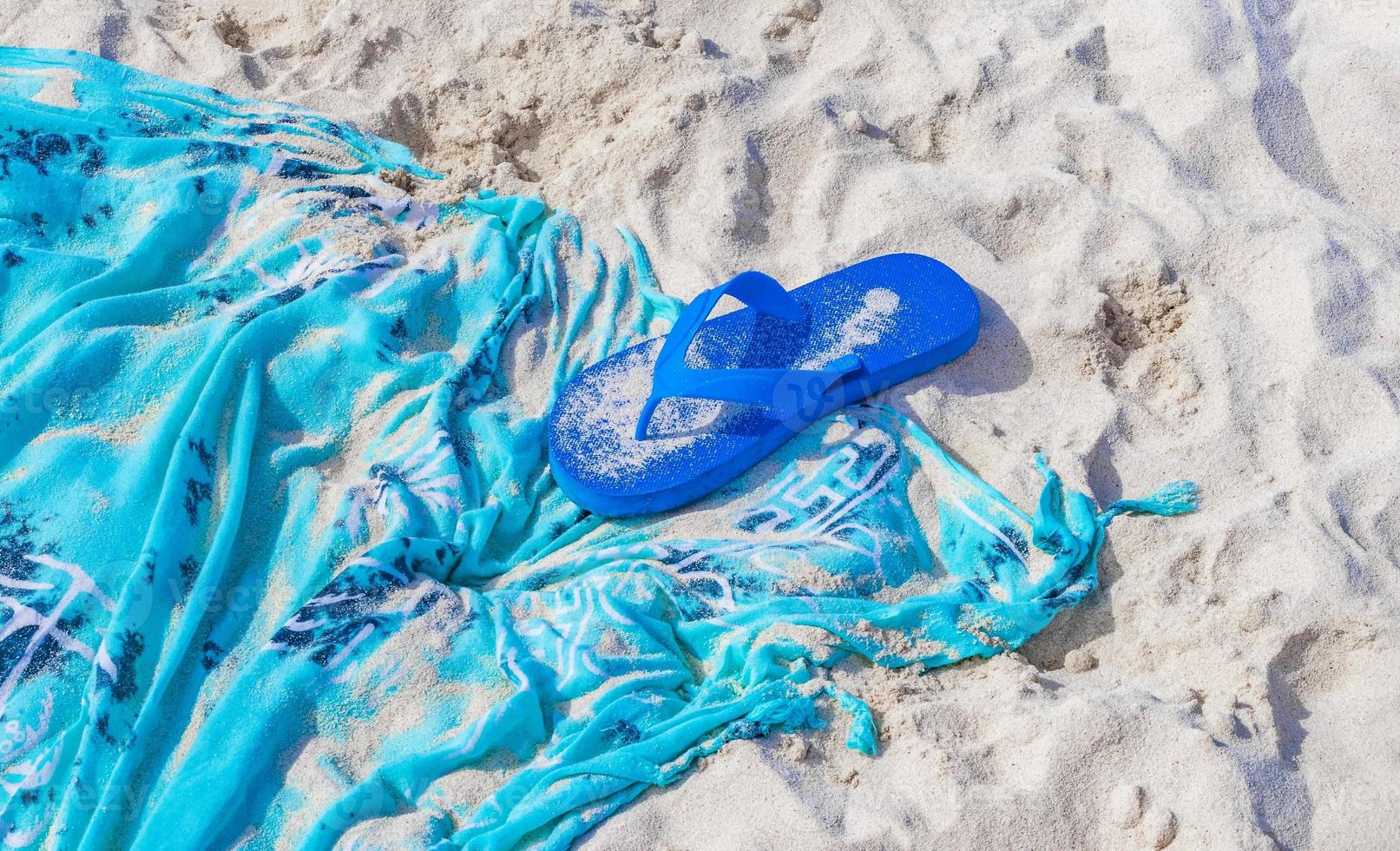 blauwe slippers op blauwe stranddeken handdoek op wit zand. foto