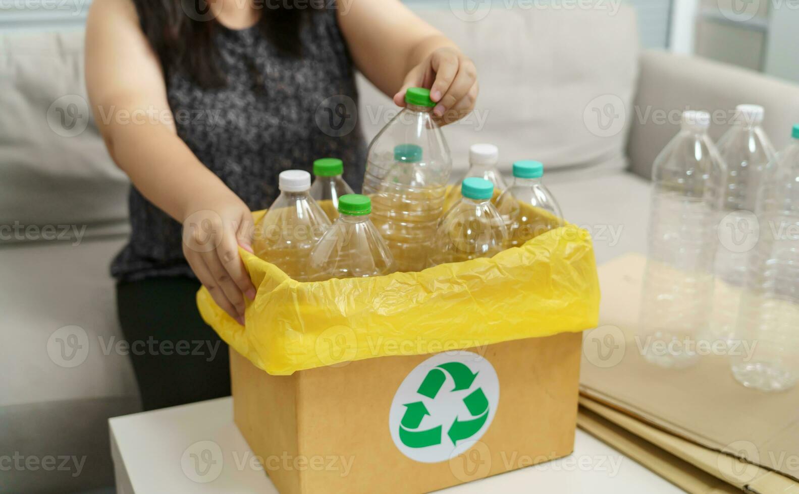 huis recycle eco groen nul concept vrouw het werpen leeg plastic fles in recycling bak met geel vuilnis Tassen Bij huis. foto
