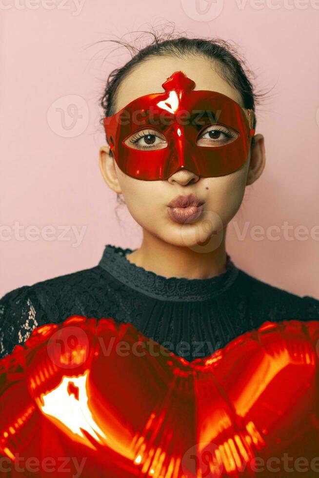 vrouw vervelend maskerade masker en Holding hart vormig lucht ballon. valentijnsdag dag, verjaardag, verjaardag, feestelijk, bal viering concepten foto