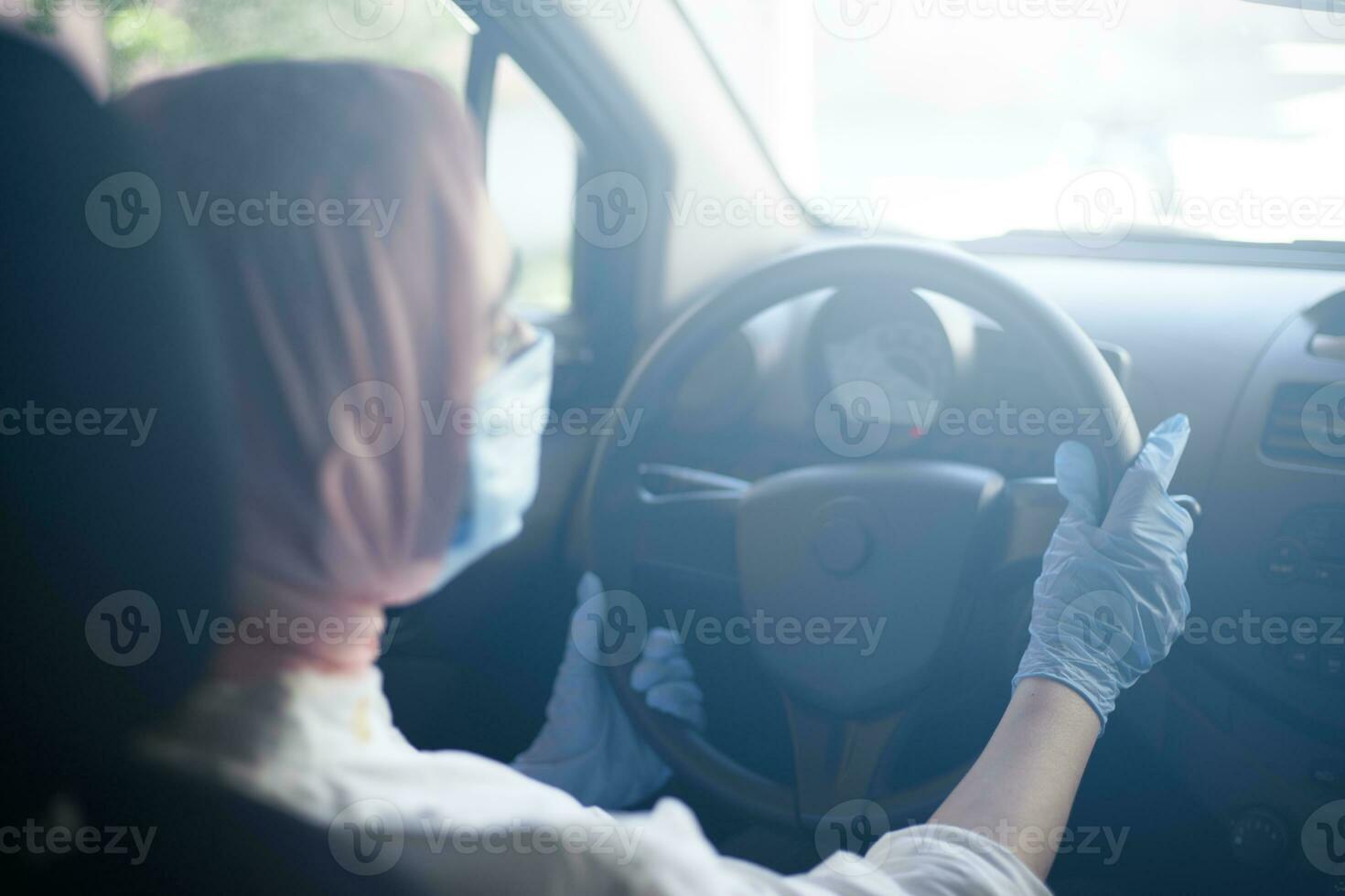 moslim vrouw in gezicht masker en handschoenen het rijden auto foto