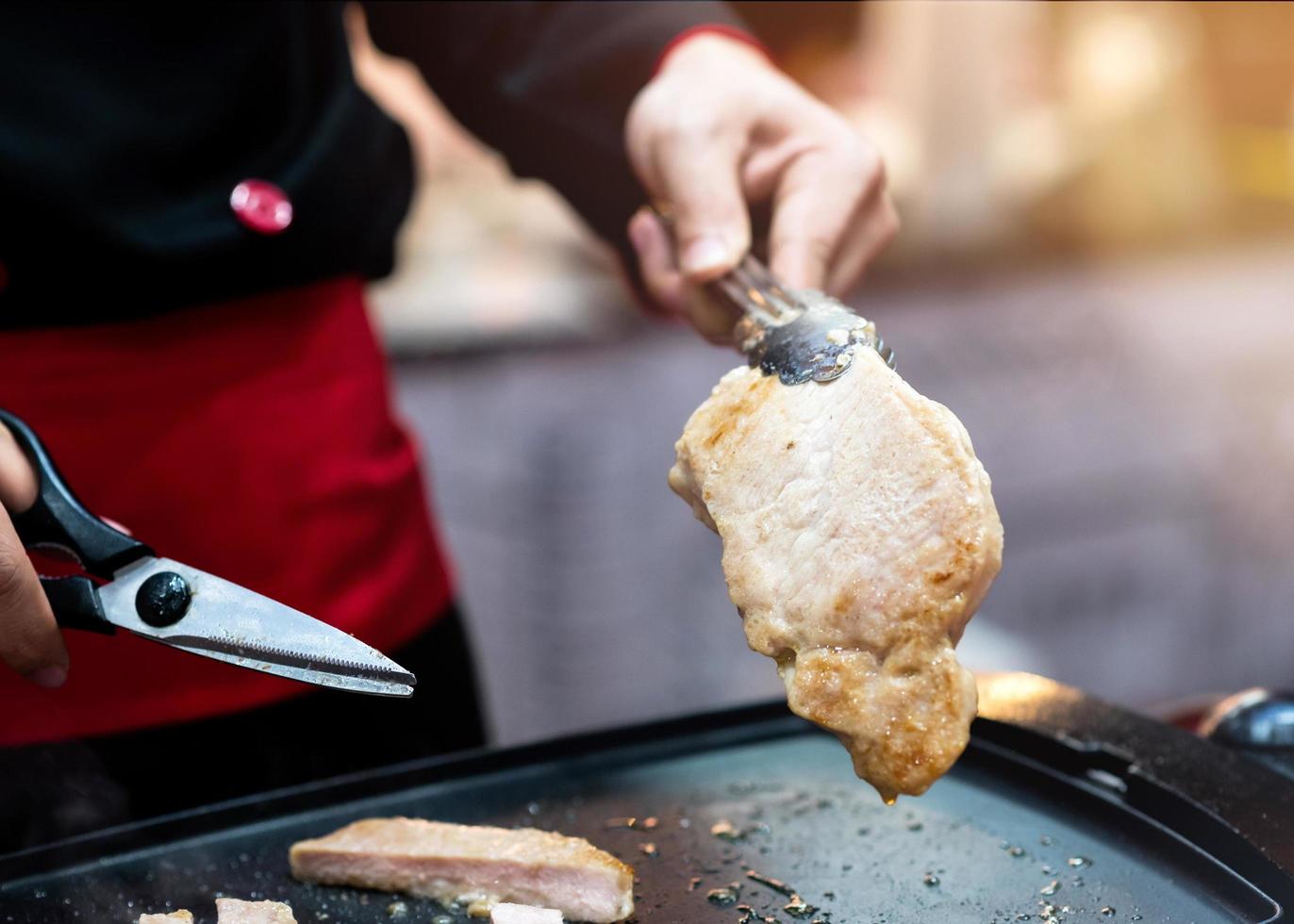 Handgreepschaar die gegrilde varkenssteak snijdt foto