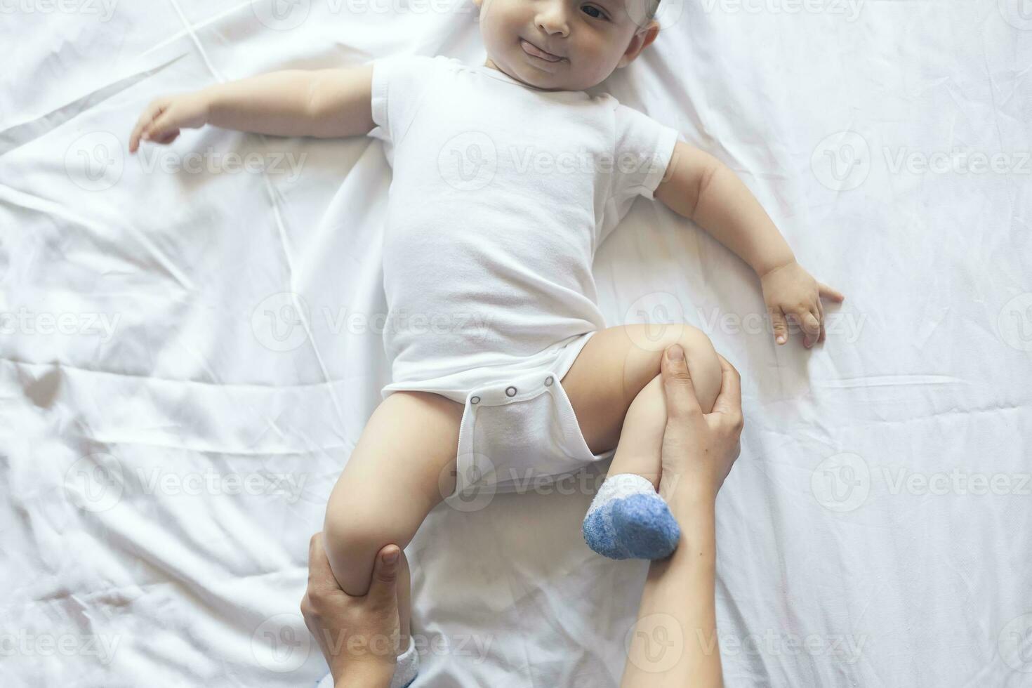 baby massage. mam aan het doen gymnastiek met kind. mama masseren schattig baby jongen. in beweging baby's poten naar helpen verlichten constipatie. jong moeder aan het doen opdrachten en bewegingen naar stimuleren baby's darmen. foto