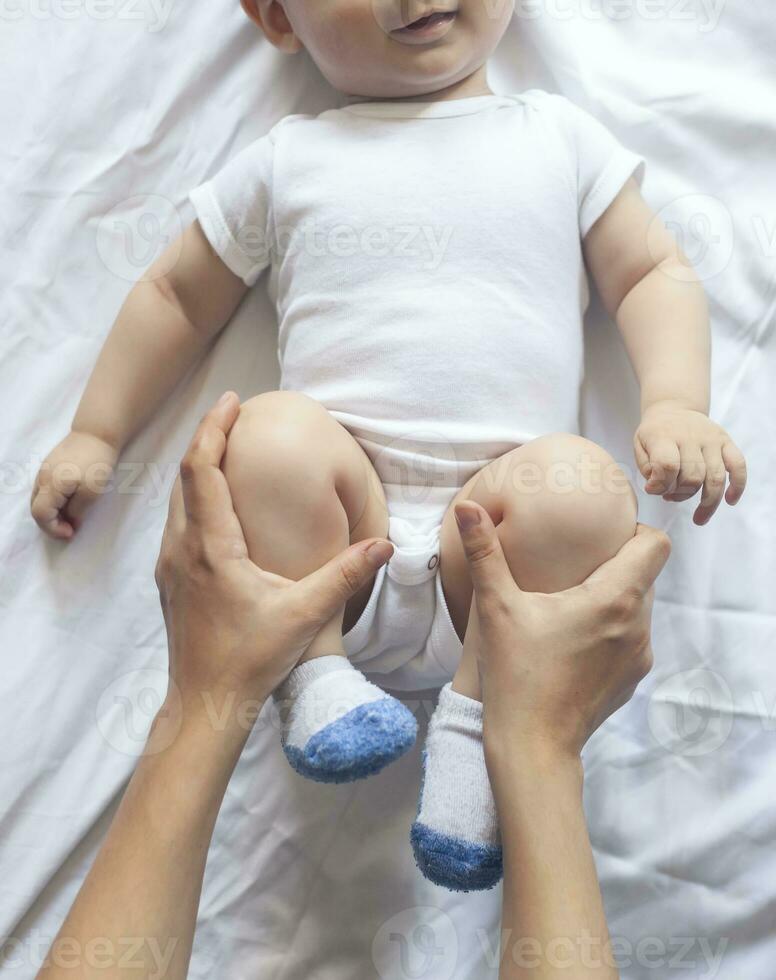 baby massage. mam aan het doen gymnastiek met kind. mama masseren schattig baby jongen. in beweging baby's poten naar helpen verlichten constipatie. jong moeder aan het doen opdrachten en bewegingen naar stimuleren baby's darmen. foto