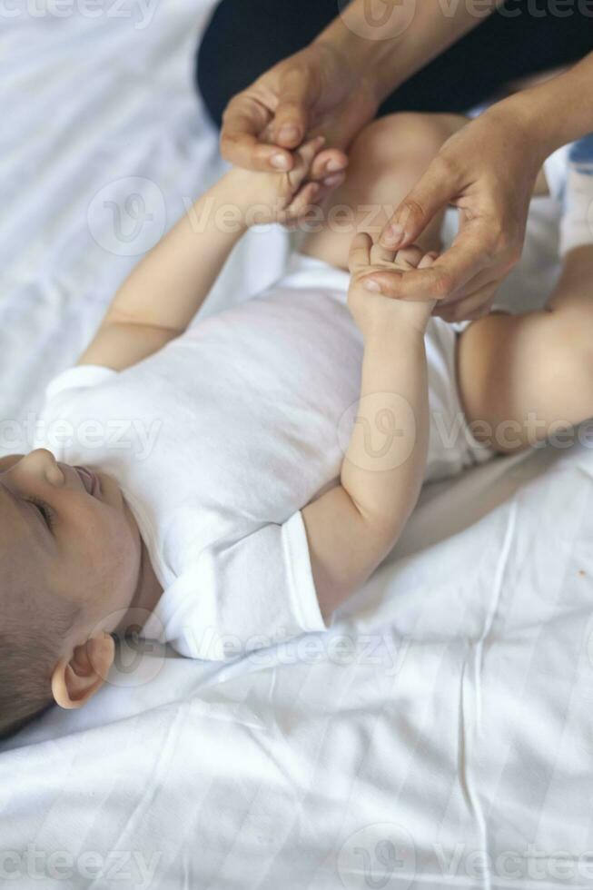 baby massage. mam aan het doen gymnastiek met kind. mama masseren schattig baby jongen. in beweging baby's poten naar helpen verlichten constipatie. jong moeder aan het doen opdrachten en bewegingen naar stimuleren baby's darmen. foto