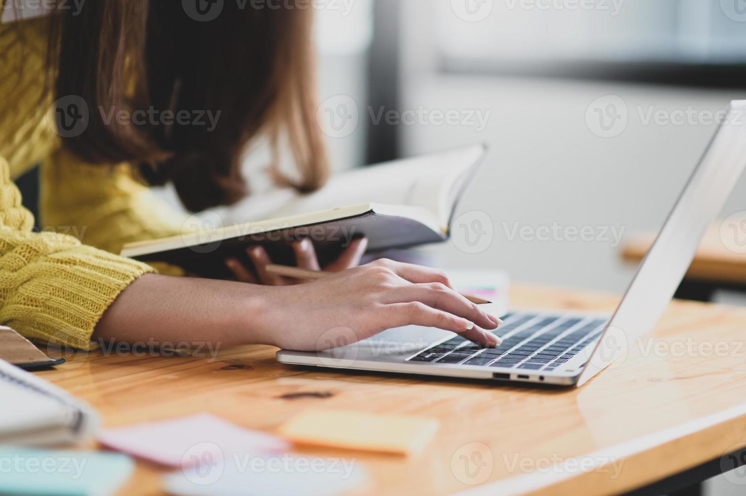 meisje met behulp van laptop en een boek in de hand te houden. foto