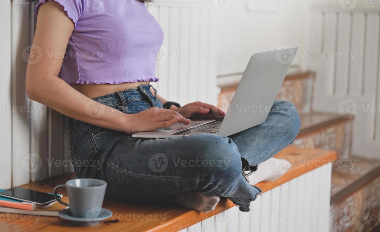 tienermeisje draagt een t-shirt met haar taille met behulp van een laptop. foto