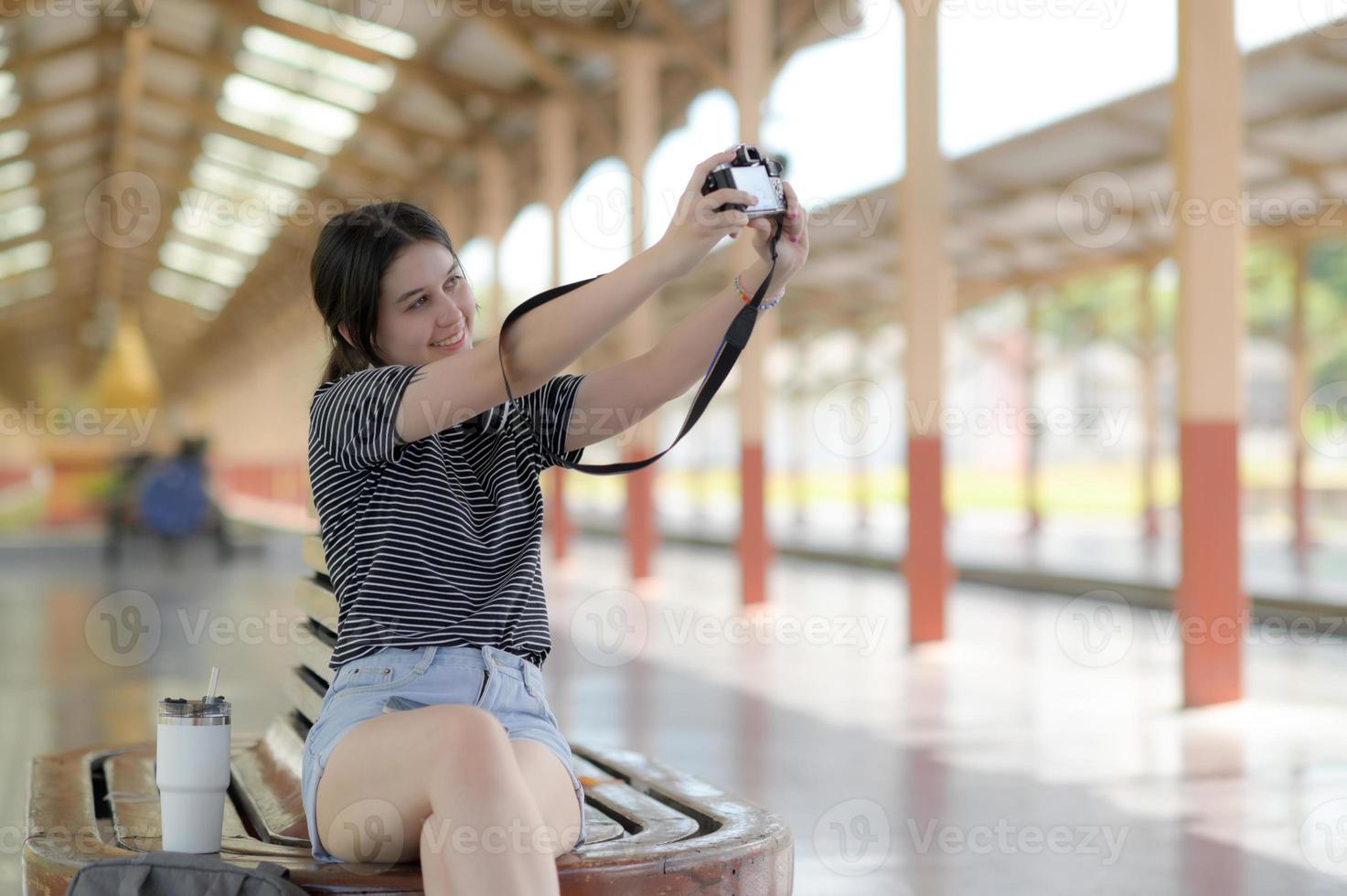 een vrouwelijke tienertoerist neemt een selfie terwijl ze wacht op een reis. foto