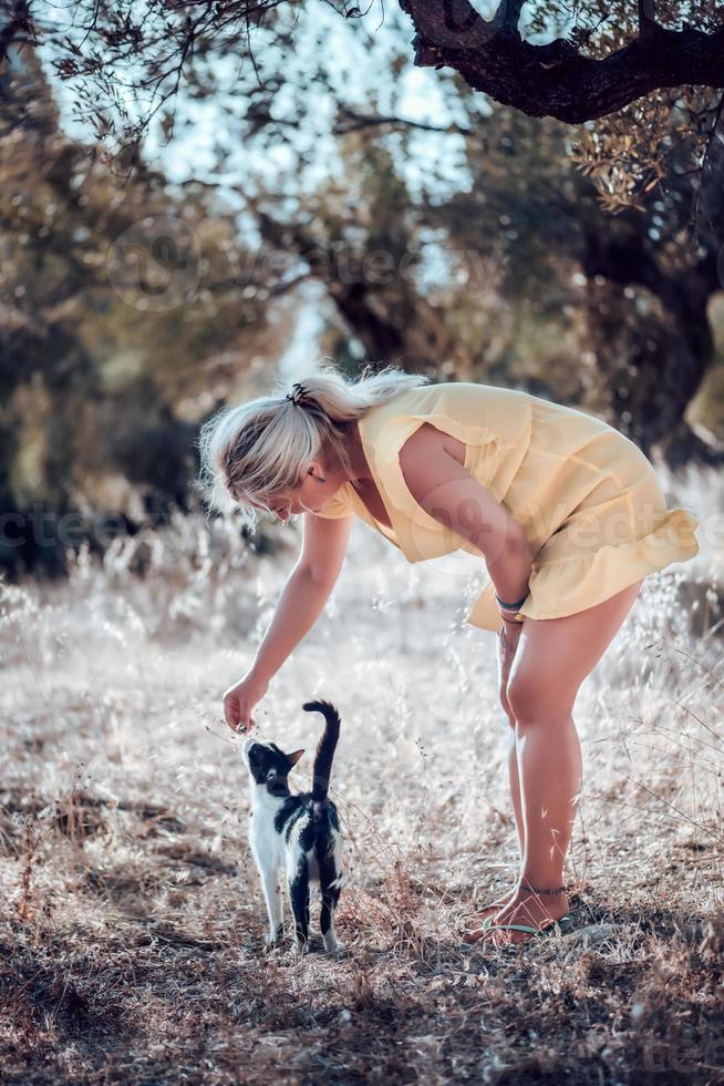 een blonde vrouw op blote voeten in een gele zomerjurk foto