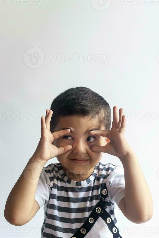 zes jaren jongen portret. onschuldig glimlachen weinig jongen Aan grijs achtergrond. weinig jongen verdraait zijn gezicht. mensen, kinderjaren levensstijl concept. foto