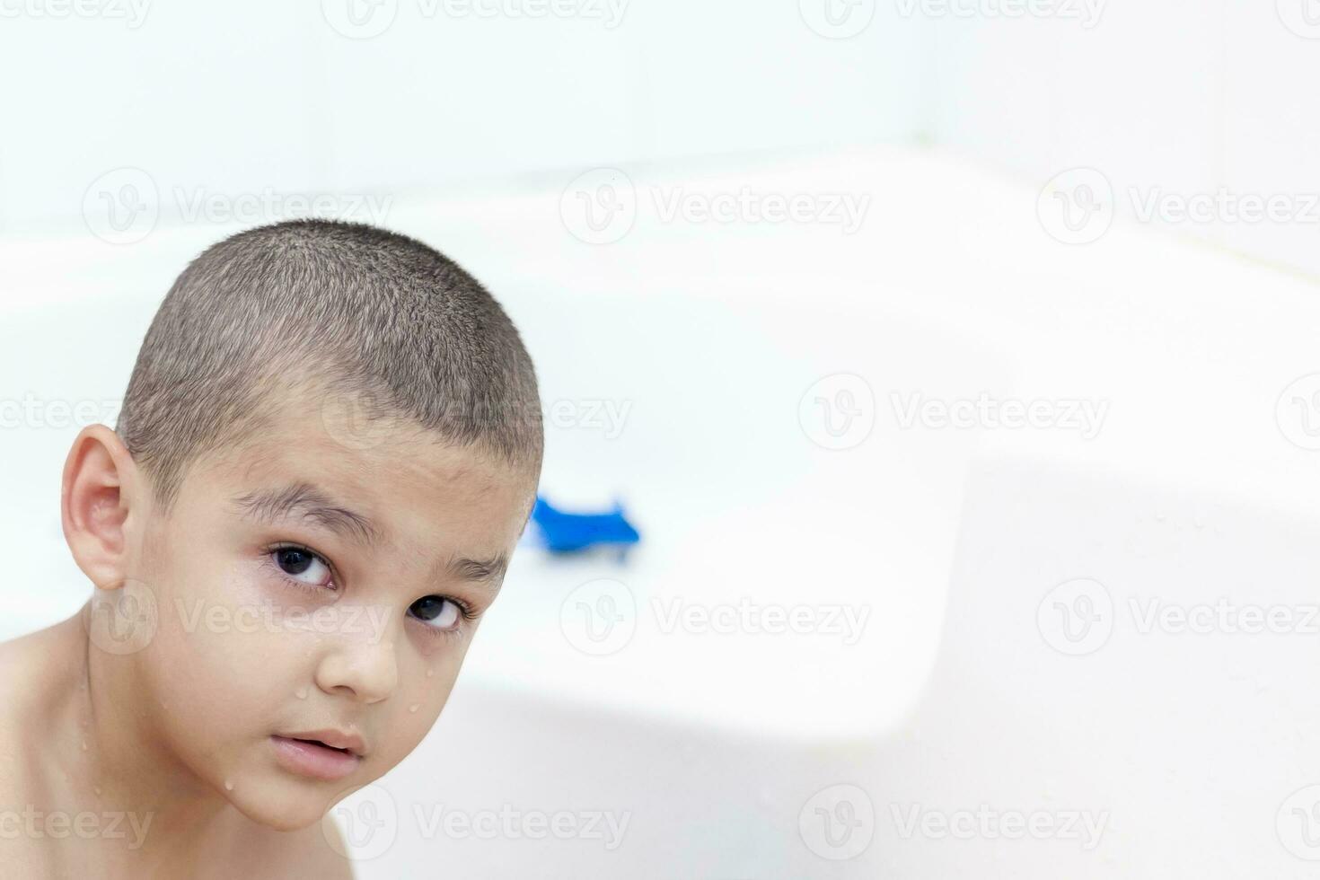 jongen duurt een bad. 5-6 jaren kind hebben water pret in badkamer. foto