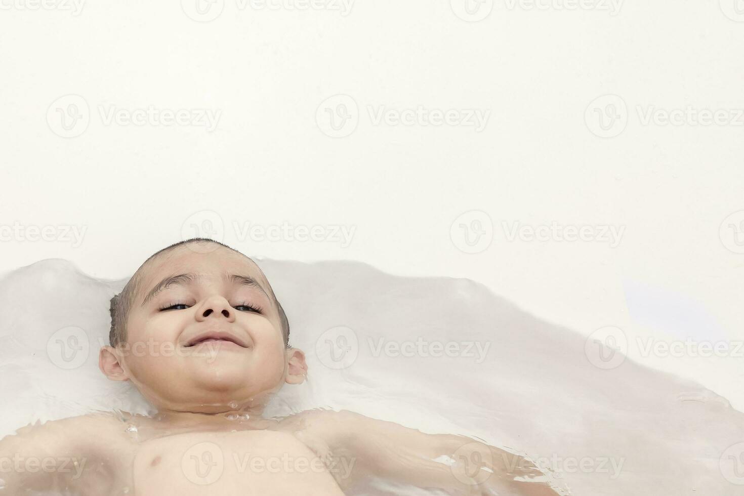 jongen duurt een bad. 5-6 jaren kind hebben water pret in badkamer. foto