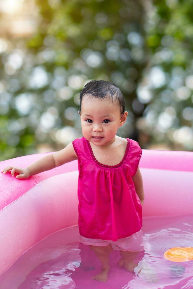 Aziatisch baby meisje spelen in een baby rubber zwembad foto