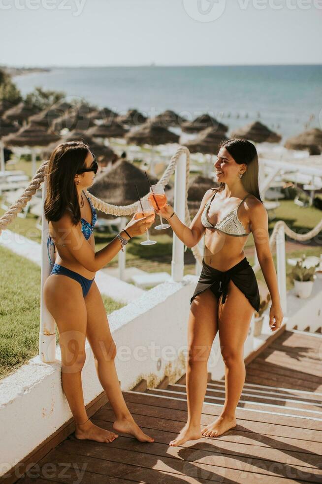 glimlachen jong Dames in bikini genieten van vakantie Aan de strand foto