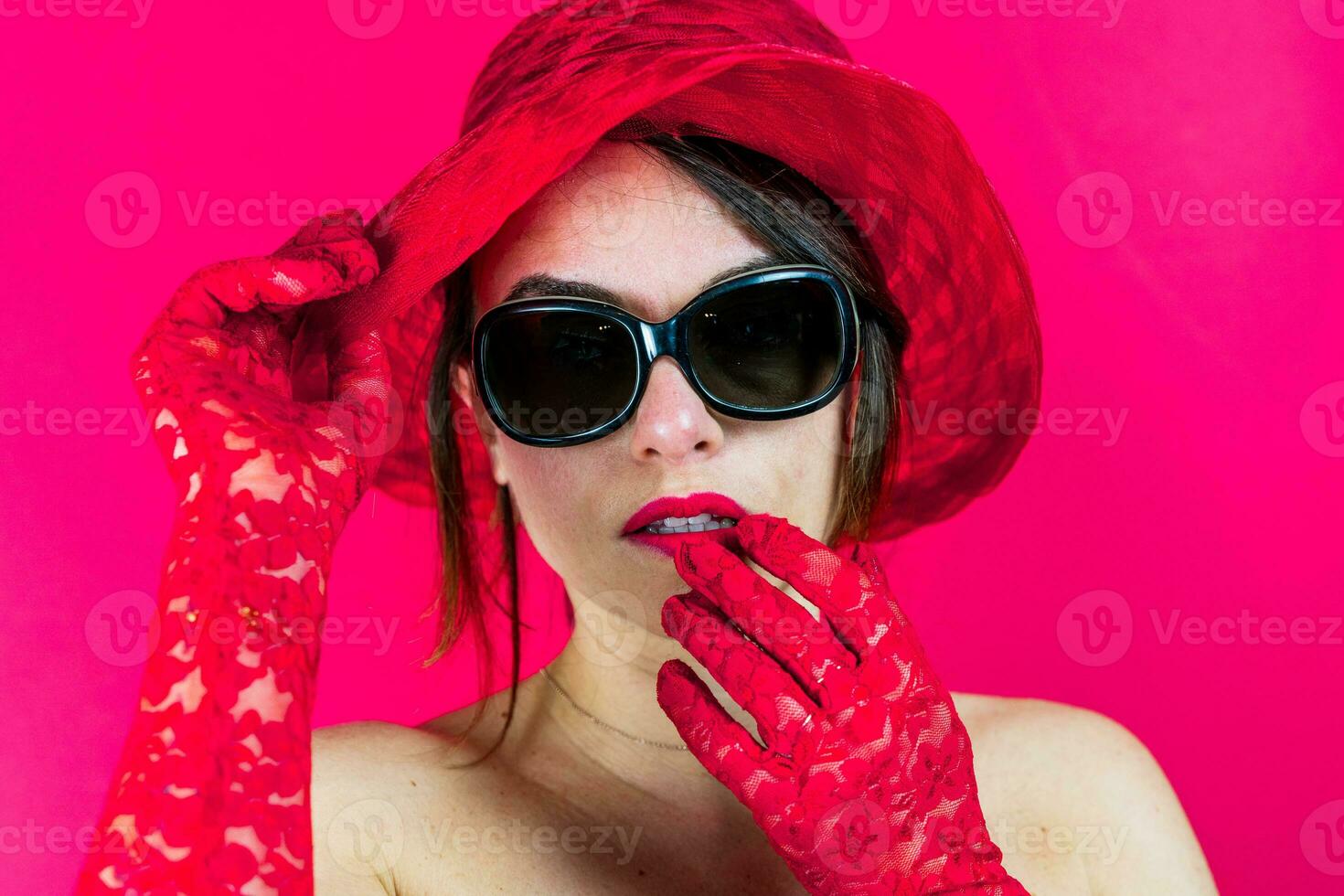 portret van schattig jong vrouw vervelend hoed en rood handschoenen Aan rood achtergrond foto