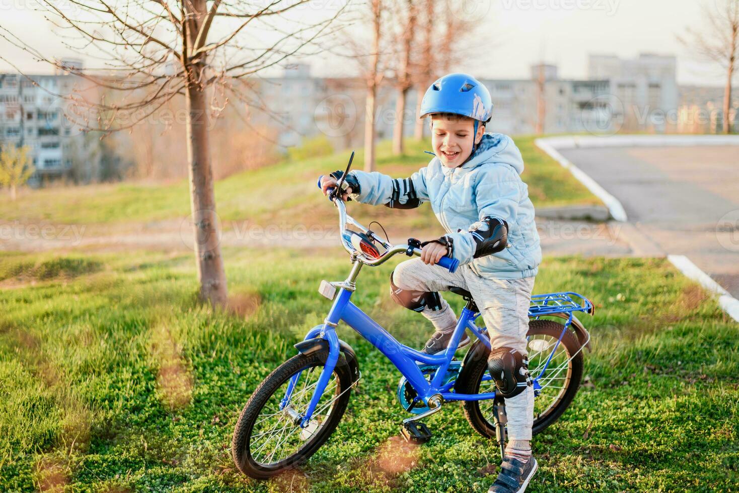 een kind in een helm leert naar rijden een fiets Aan een zonnig dag Bij zonsondergang foto